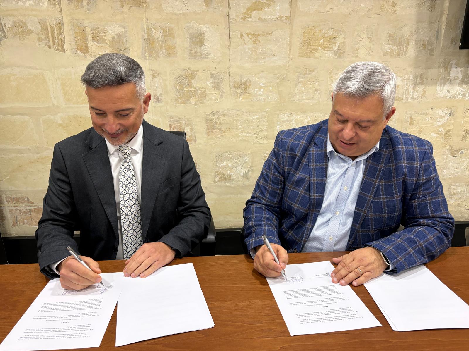 MCA and FITA representatives signing documents while seated at a table